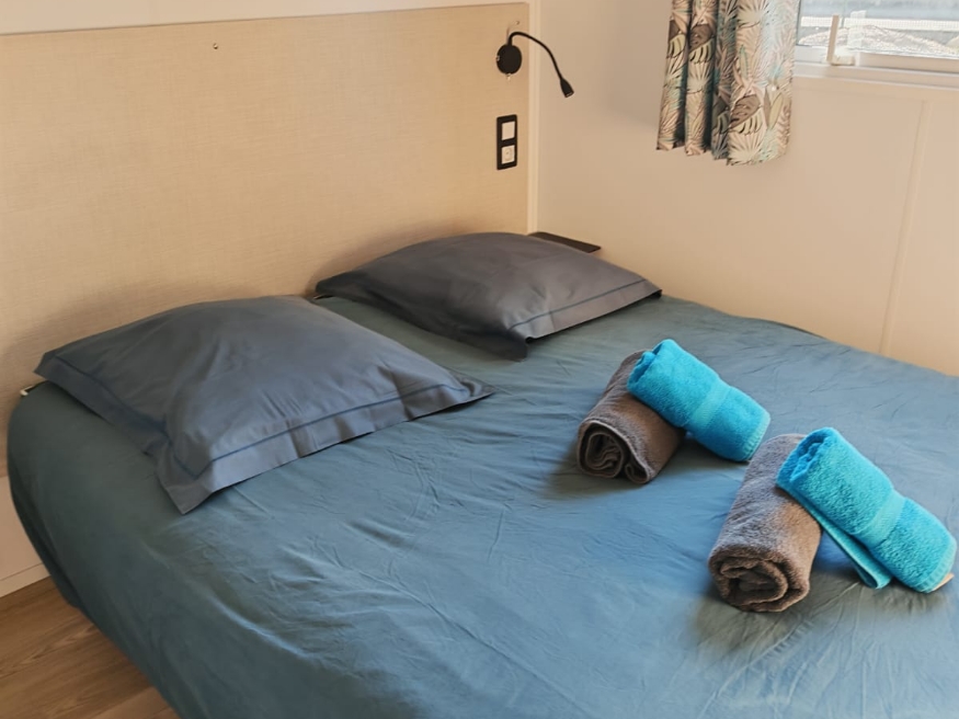Bedroom with double bed in the Grand Large mobile home, available for rent at Le Paquier Fané campground in Saône-et-Loire
