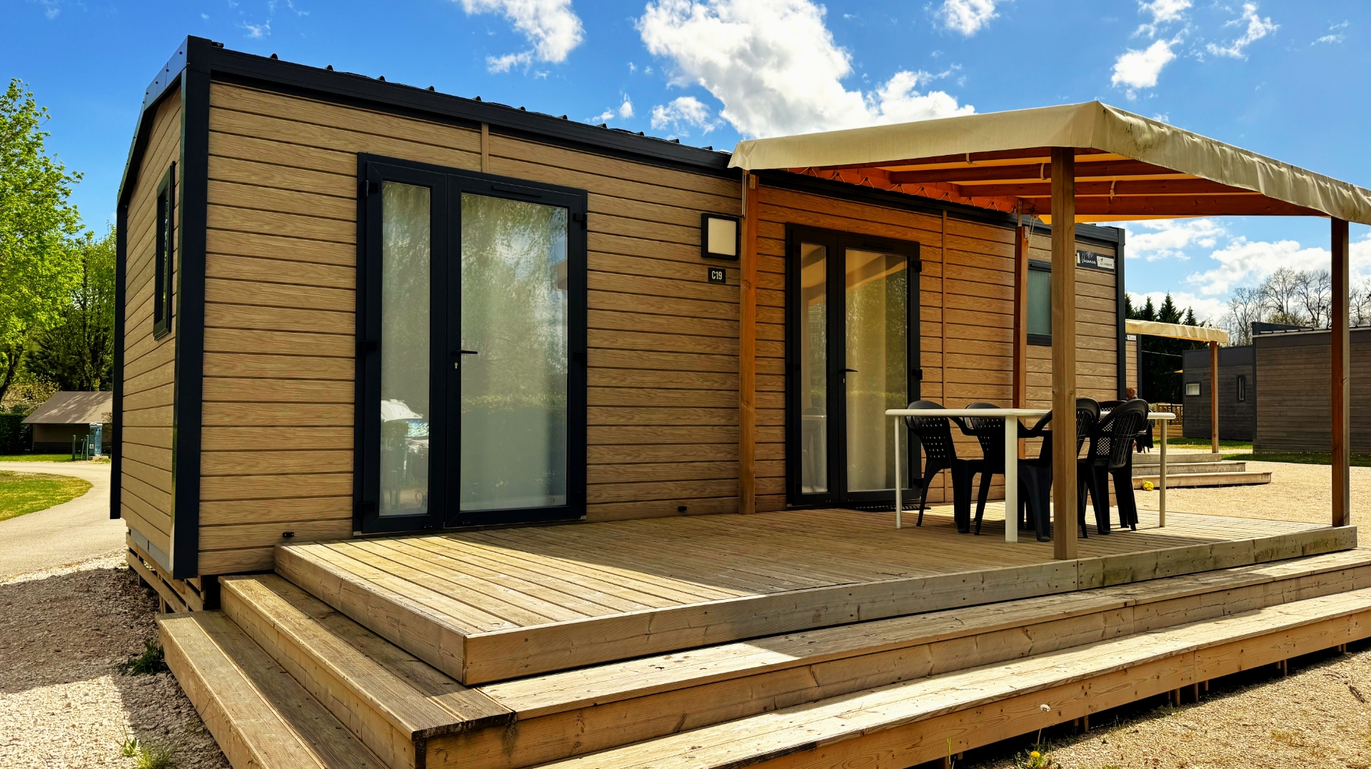 Exterior view of the Grand Large mobile home with covered terrace, available for rent at Le Paquier Fané campground in Saône-et-Loire