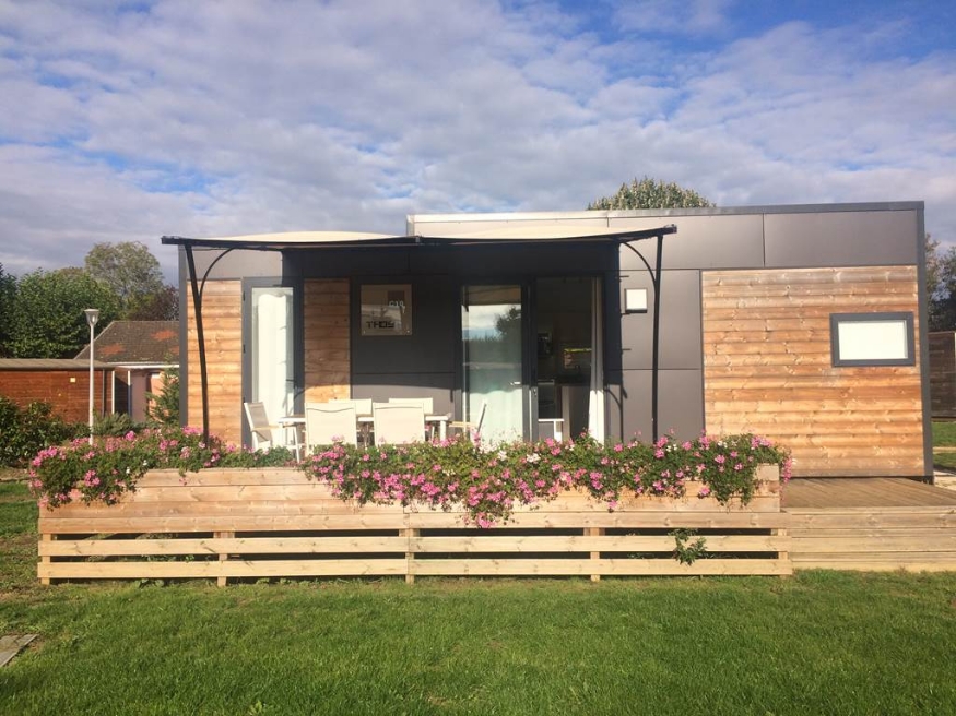 Exterior view of the TAOS luxury mobile home with outdoor terrace, available for rent at Le Paquier Fané campground in Bourgogne-Franche-Comté