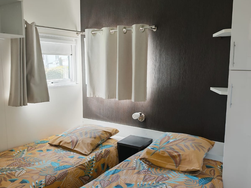 Bedroom with two single beds in the TAOS luxury mobile home, available for rent at Le Paquier Fané campground in Chagny, Saône-et-Loire