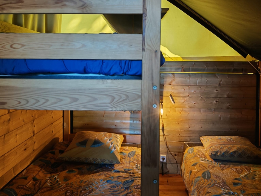 Sleeping area with bunk beds in the unusual Safari tent accommodation in Saône-et-Loire, available to rent at the 3-star Le Paquier Fané campsite in Chagny, Bourgogne-Franche-Comté.