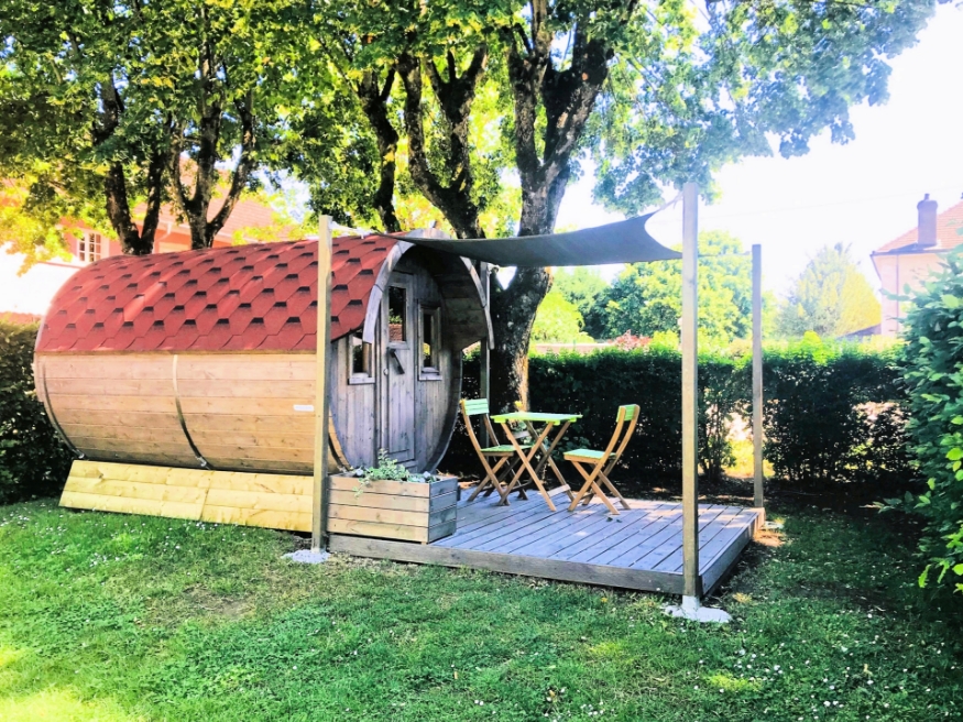 General view of the unusual barrel accommodation with a threshold designed for breakfast in the sun and starry evenings, available for rent at the 3-star Le Paquier Fané campsite in Saône-et-Loire.